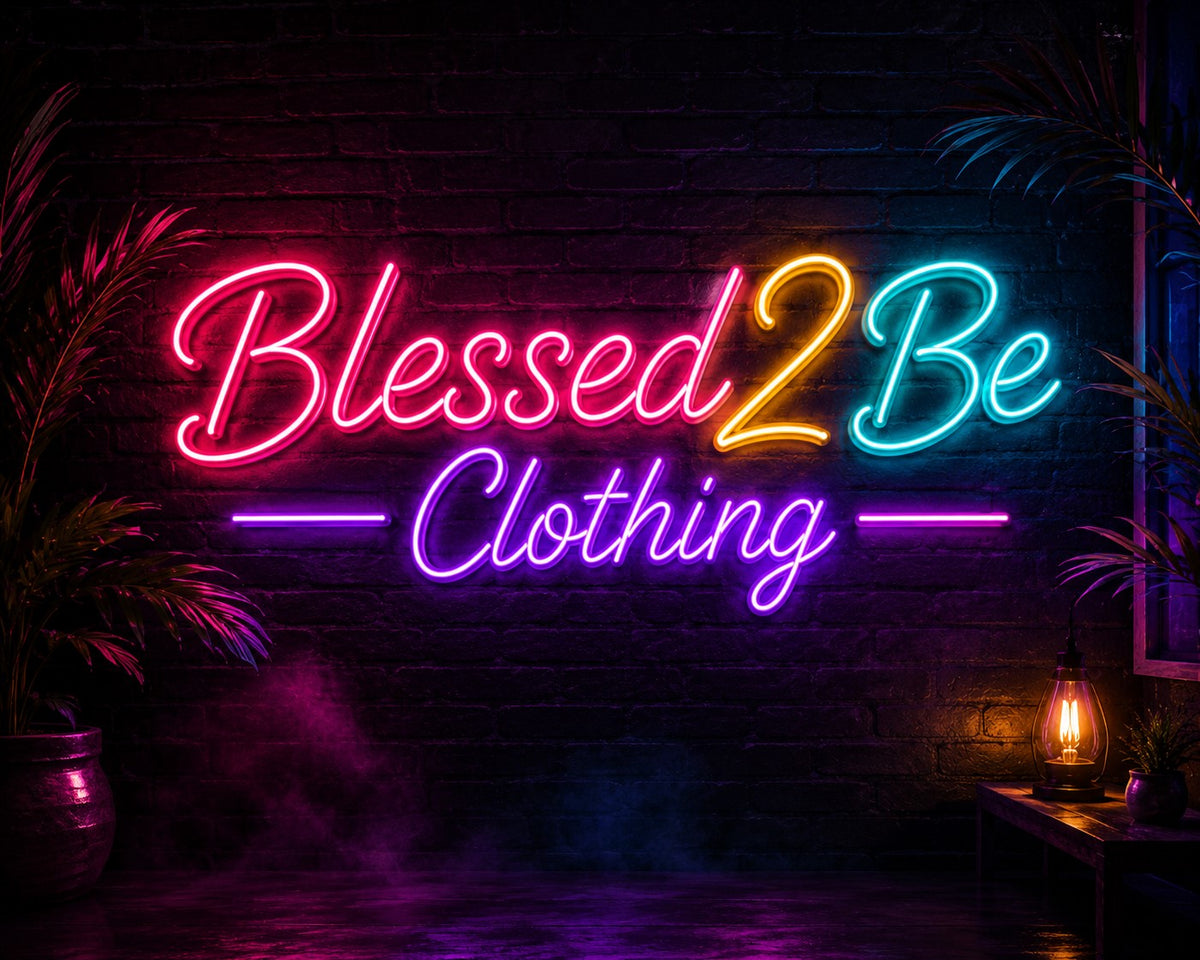 A colorful neon sign reading 'Blessed2Be Clothing' mounted on a dark brick wall, with glowing pink, yellow, blue, and purple lights, flanked by plants and a small lamp in a dim interior.